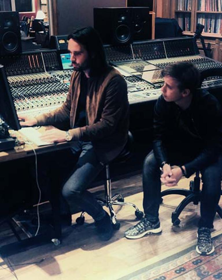 A musician and a producer sitting together in a studio working on a song